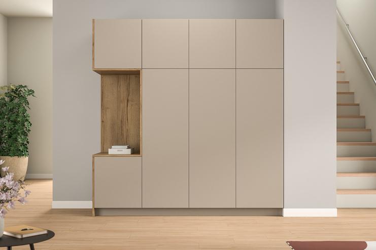 Ein minimalistischer, maßgefertigter Schrank mit hellen und holzfarbenen Elementen, integriert neben einer Treppe, bietet stilvollen Stauraum im Eingangsbereich.